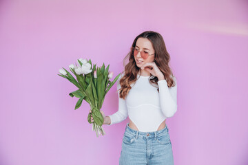 Beauty girl holding Spring tulips Flower bouquet and smiling. Happy Beautiful woman receiving a Bunch of colorful Tulip flowers. Surprised model. Valentine's Day. Mother's Day. Birthday party