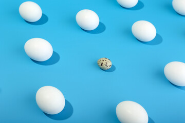 broken pattern with quail egg among chicken eggs on blue background