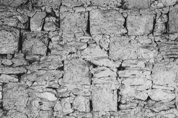 A black-and-white image of a stone wall texture. Texture of a wall made of rough stones.