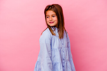 Little caucasian girl isolated on pink background  looks aside smiling, cheerful and pleasant.
