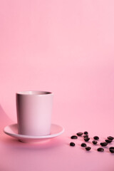 Pink cup of coffee with pink background and coffee beans