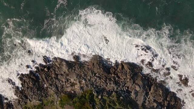 Plano a&eacute;reo zenital desde drone de mar picado con olas con mucho viento chocando contra rocas en la costa.