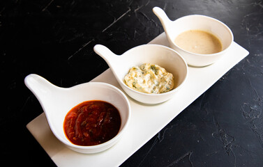 three kinds of sauce in white cups ketchup mayonnaise and sauce