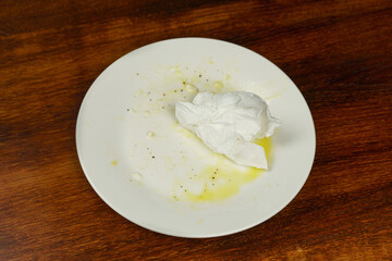 An empty dirty plate with a crumpled napkin