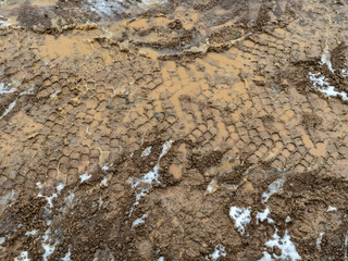 Heavy equipment tire tracks in wet mud at a construction site. The problem of road contamination.