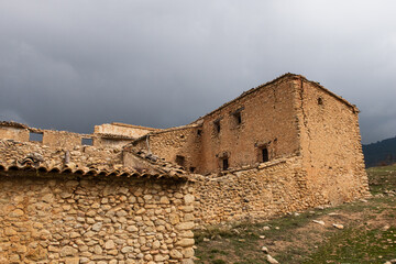 Large abandoned Mediterranean style stone built country house isolated in a field on a very cloudy...