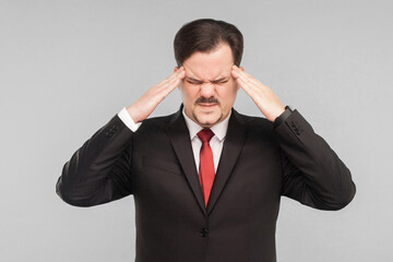 Problems at work, symptoms of disease. Man holding head and have migraine. studio shot. isolated on gray background. handsome businessman with black suit, red tie and mustache. closed eyes.