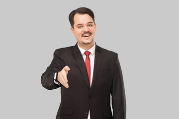 Congratulations you are hired, you will have your office and assistant. indoor studio shot. isolated on gray background. handsome businessman with black suit, red tie and mustache looking at camera.