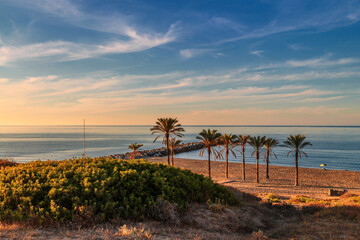 Fototapeta na wymiar Beach with palm trees in sunset lights.