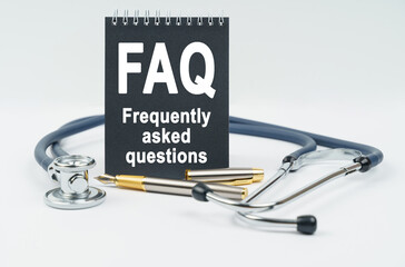 On a white background lies a stethoscope, a pen and a black notebook with the inscription - FAQ