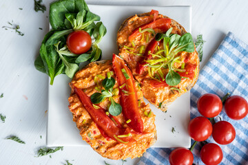 vegan roasted red pepper dip sandwich spread on freshly baked bread slice with salad garnish on white porcelain plate 