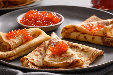 Russian thin pancakes with red caviar on grey. Traditional religion breakfast for national holiday Shrovetide. Maslenitsa. Close up.