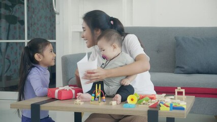 Happy young asian mother day, daughter giving postcard with mom and kiss cheek at living room, children giving greeting card with parent in celebrate birthday with excited at room, family concept.