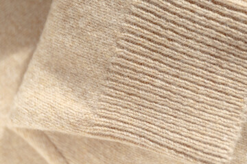 Fototapeta na wymiar Details of a knitted wool sweater, textured background. A folded cashmere knit sweater in a beige shade. Stylish knitwear