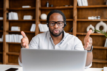 Focused African-American man is call center worker or support customer officer. Smart dark-skinned...