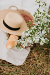 picnic on the grass, a baguette and a bouquet of flowers in a basket straw hat