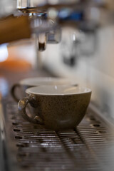 macro of espresso coffee cups in professional coffee machine with blurred backround