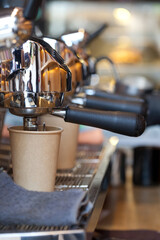 modern professional espresso machine with coffee pouring into take away paper cup