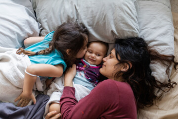 Mother and her two young daughters lying down in bed