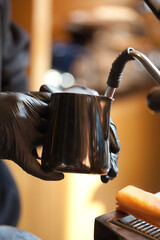 barista hands steaming milk for coffee in modern espresso machine