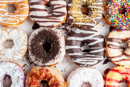 Flat lay top view image of a dozen donuts on card board box. A delicious assortment with different flavors and toppings. A vibrant colorful variety pack. A tradition for parties in USA
