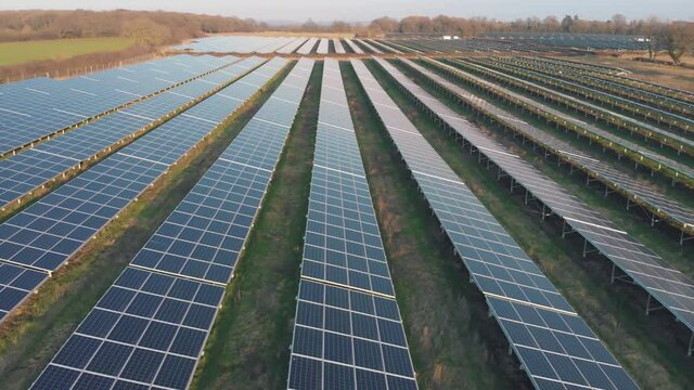 Aerial drone shot of rows of solar panels in green countryside landscape