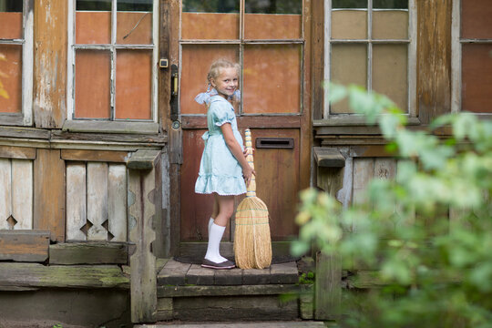 a girl with a broom helps her mother sweep on the porch of the house. Children are helpers. Cleaning the house. Children Russia, USSR