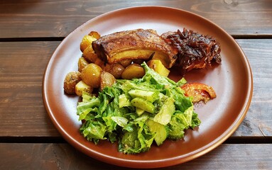 Grilled pork ribs and oven baked potatoes on a ceramic plate in the village