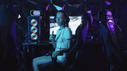 Girl gamer sits at the computer in the gaming club - turns around and vaping