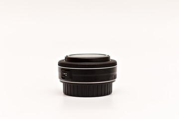 Small thin black pancake lens for DSLR camera with caps on on white background