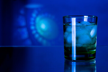 a glass of whiskey in blue and with a lot of ice