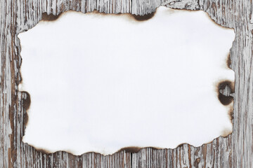 White charred sheet of paper on a light wooden background