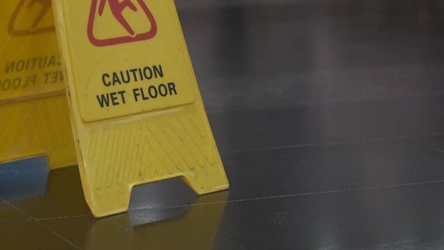 Sign Caution Wet Floor. Yellow plaque in the mall.