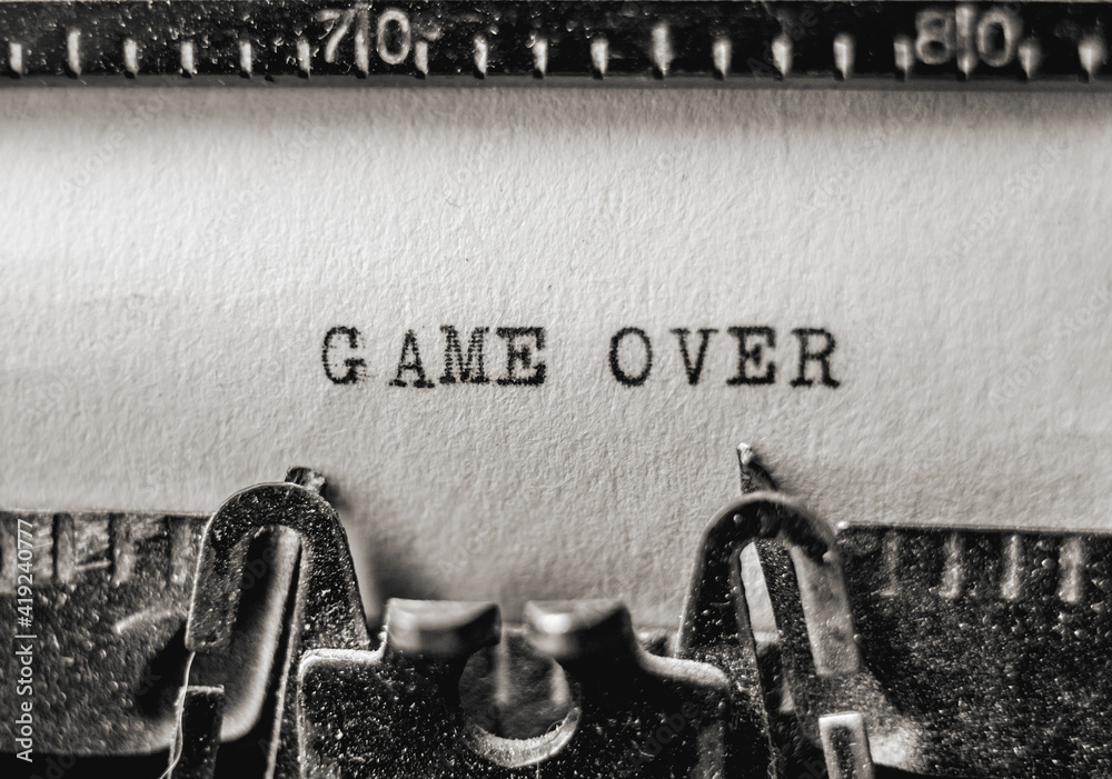 Fototapete text game over printed on old paper sheet using black inks on retro typewriter. closeup view
