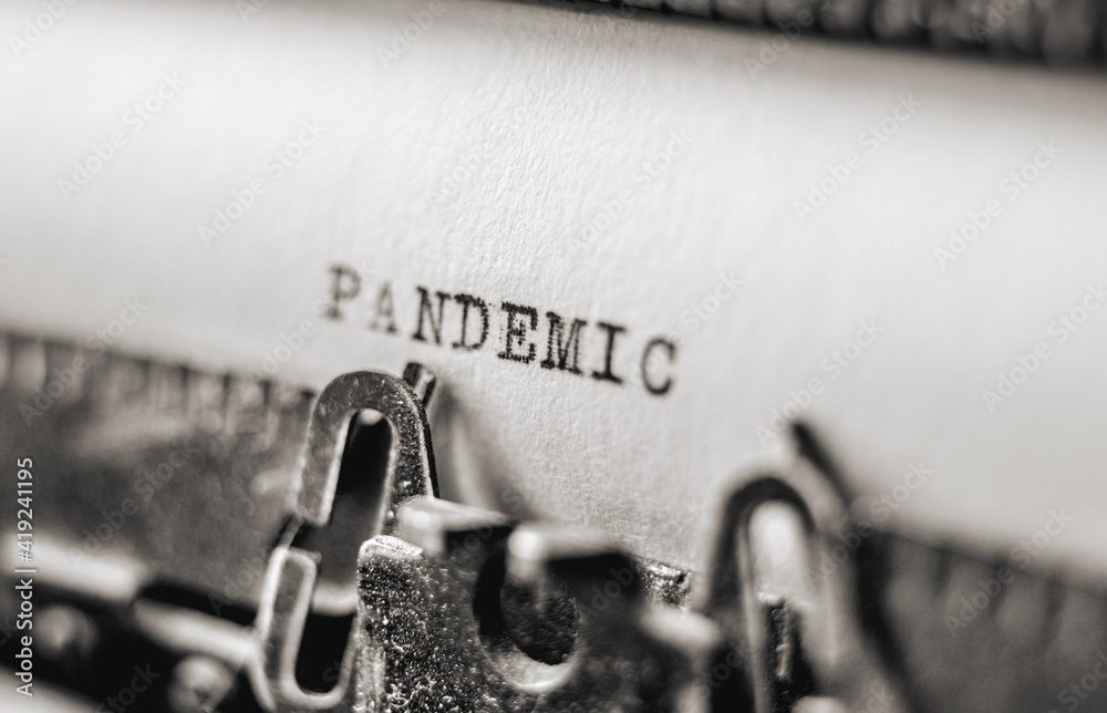 Fototapete text pandemic printed with black inks on old white paper on retro typewriter with typographic font
