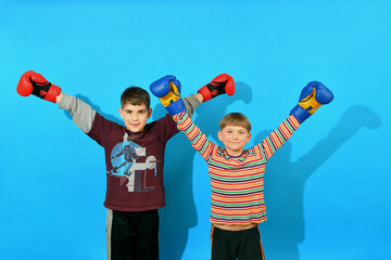 Two joyful young boxers in boxing gloves raised their hands to the top as a sign of common victory.