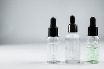 Obraz na płótnie Canvas three glass bottles of cosmetic serum on a light background