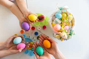 Hands of family members are holding many painted Easter eggs. Easter decoration concept