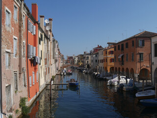 Fototapeta na wymiar Chioggia, Vena Canal with colorful ancient buildings on both sides and crossed by ancient bridges