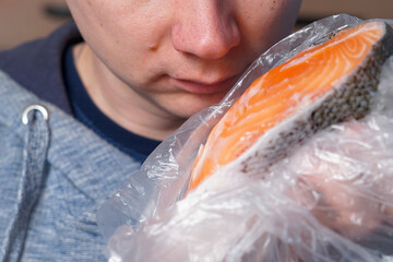 Nose near the red fish steak. Checking fish for smell. Spoiled fish