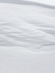 Pure white snow background texture. Winter background with snow embankments. Snow drifts after a blizzard, present. Details of the seasonal landscape. Cold weather.