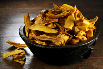 dried organic mango in a wooden bowl on wooden background
