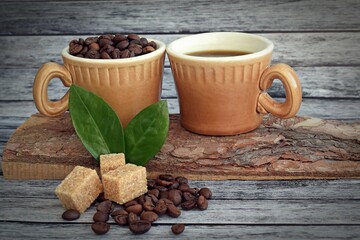 A cup of aromatic coffee,coffee beans and brown sugar on a wooden background.