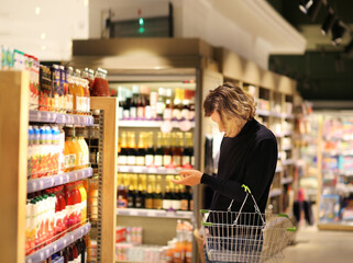 Young man shopping in supermarket, reading product information.