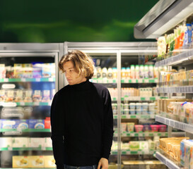 Young man shopping in supermarket, reading product information.