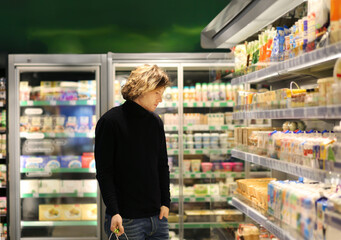 Young man shopping in supermarket, reading product information.