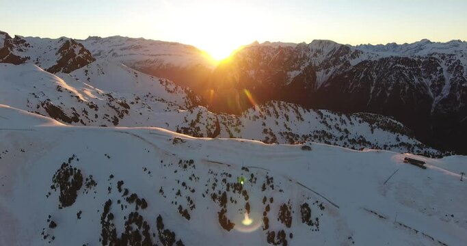 Chamrousse French alps with sunrise between the peaks, Aerial flyover approach shot