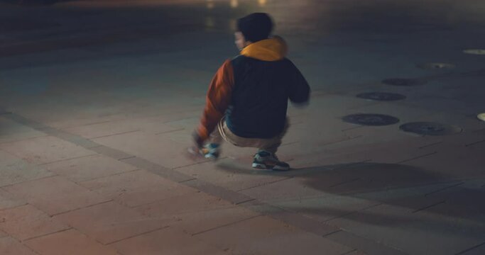Cool hip young dancer impressive breakdancing moves in city street at night