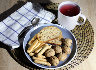 plate with bread and nuts. bread sticks with poppy seeds in a blue dish. fruit drink from red currant and wild berries. breakfast in the village.