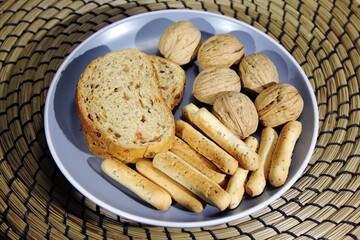 plate with bread and nuts. bread sticks with poppy seeds in a blue dish.